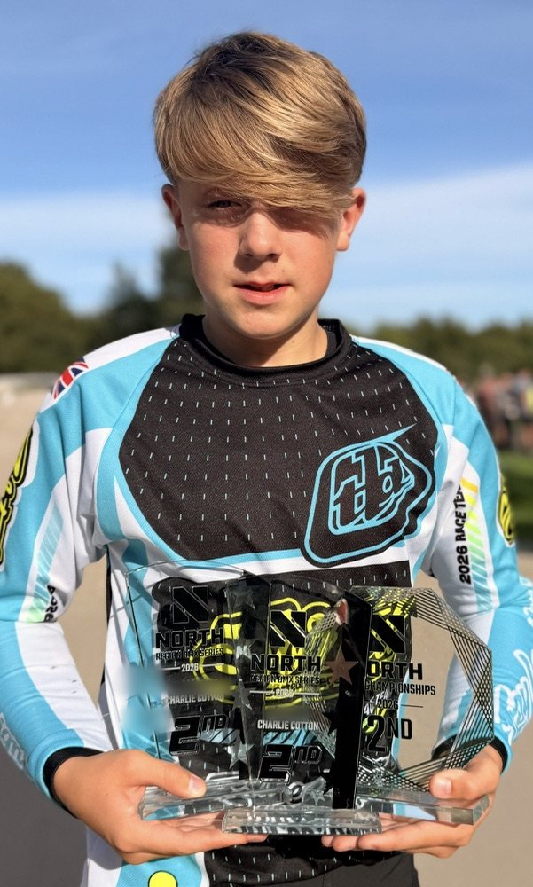 Charlie in his 2026 Troy Lee Designs and Sorted race jersey, holding three glass trophies each marked 2nd