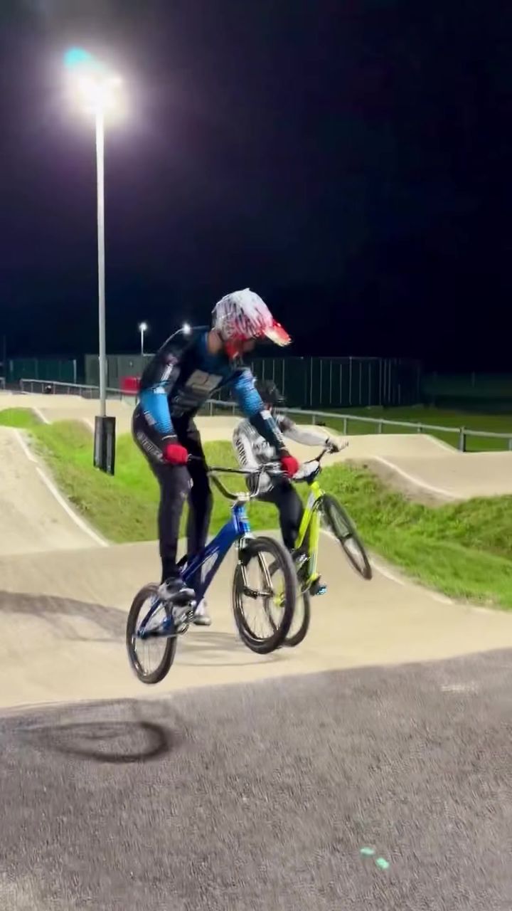 BMX riders racing under floodlights at night
