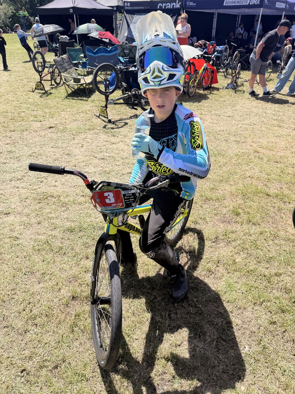 Charlie on his bike in the pits in race kit, visor up