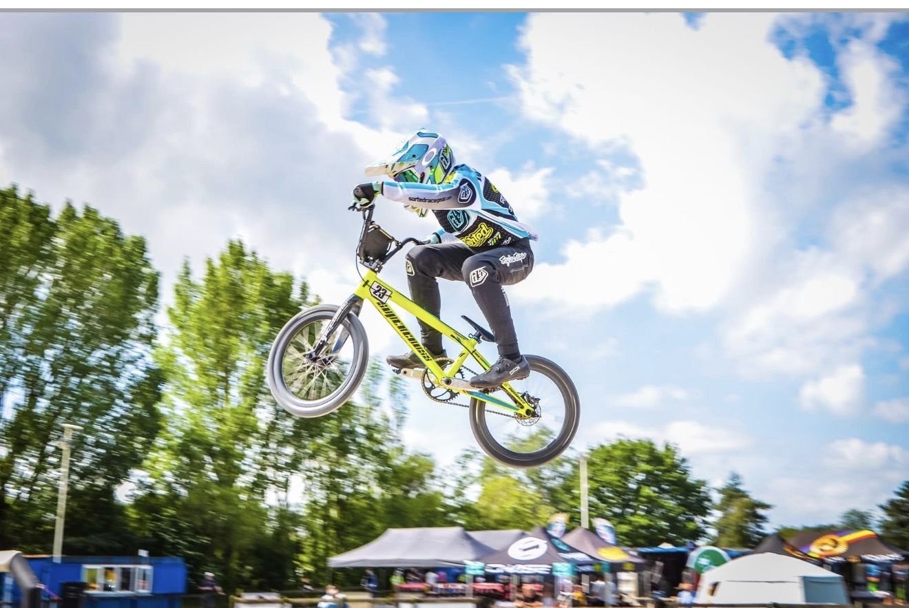 Charlie high in the air over a jump against a blue sky