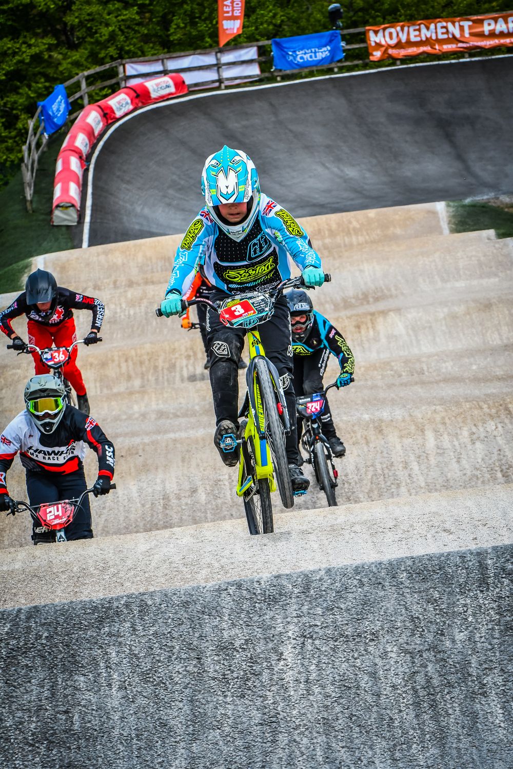 Charlie rolling off the top of a start hill ahead of other riders